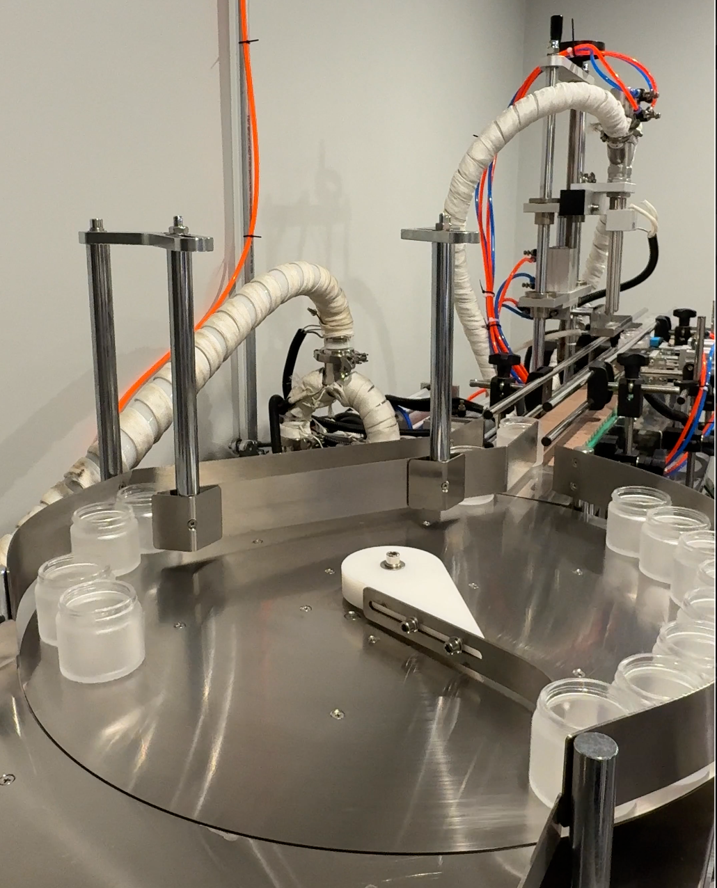 Open jars on the circular infeed table leading onto the Amadeus Apothecary filling-line conveyor.