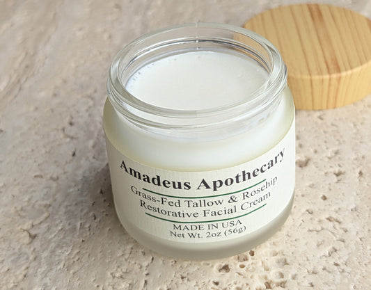 Open Amadeus Apothecary facial cream jar showing the white cream, with its wood-patterned lid beside it.